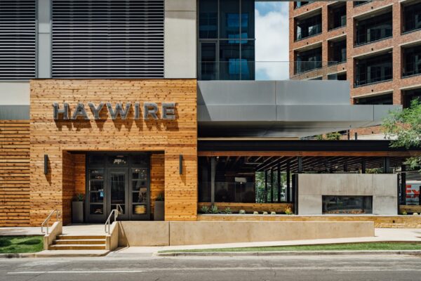 Exterior of Haywire restaurant with a modern wood facade and outdoor seating area.