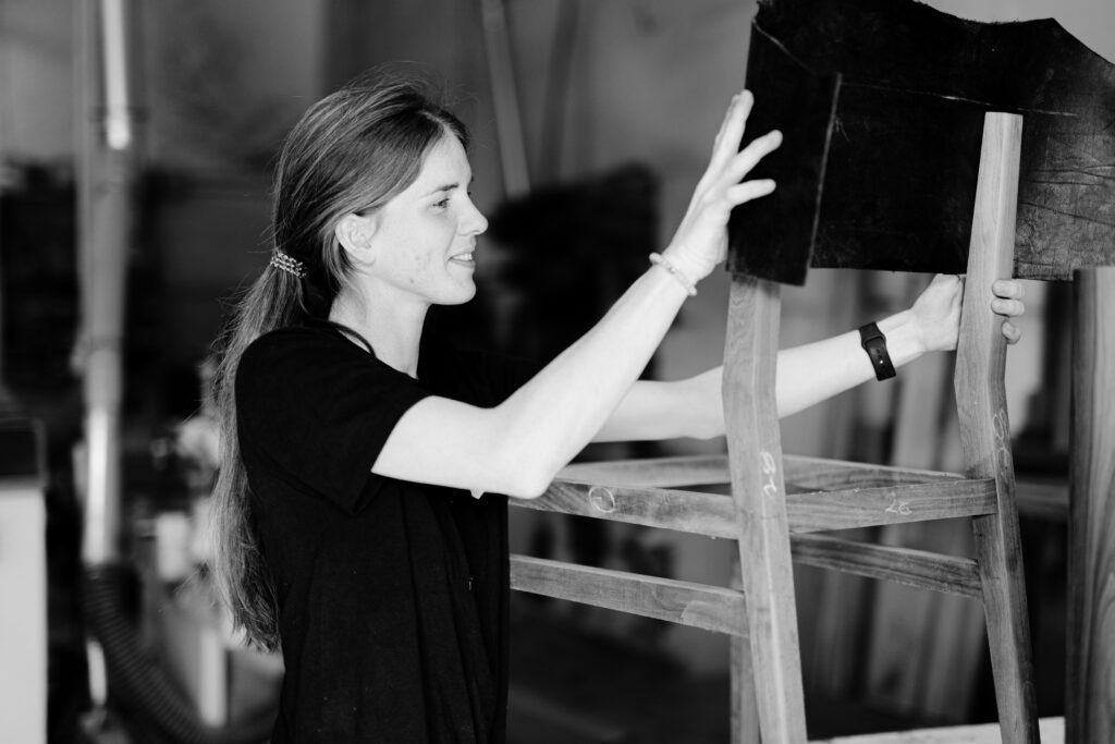 A craftswoman at South Loft working on a custom chair frame, carefully aligning its components.