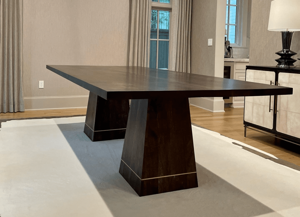 A dark brown custom dining table by South Loft with a rectangular top and sturdy geometric base.